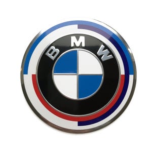 May include: A round, silver-coloured emblem with a black background and a white and blue propeller design. The letters "BMW" are in silver and surround the propeller design.