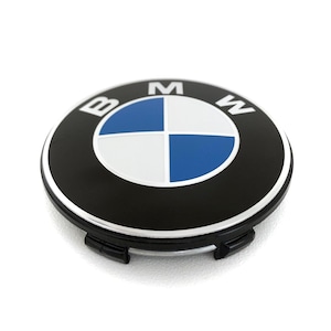 May include: A black and silver BMW wheel center cap. The BMW logo is in the center, featuring a blue and white quadrant design. The letters "B", "M", and "W" are visible around the logo. The cap has a glossy finish.