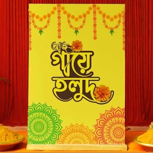 Könnte beinhalten: Ein gelbes Banner mit einer braunen Inschrift in Bengali, die "Jatra Ghul" lautet, umgeben von Girlanden aus orangefarbenen Blumen und grünen Blättern. Das Banner ist unten mit grünen, orangefarbenen und roten Mandala-Mustern verziert.