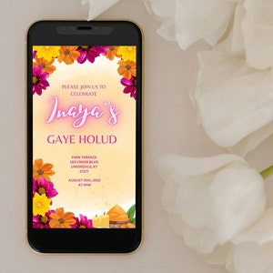 May include: A digital invitation with a floral border in shades of pink, orange, and yellow. The text reads "Please join us to celebrate Inaya's Gaye Holud" with the date and time of the event. The invitation is displayed on a smartphone.