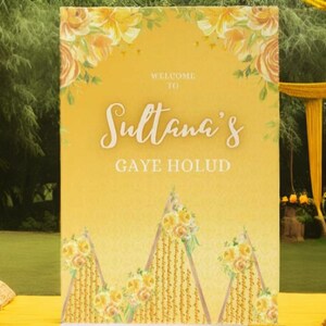 May include: A yellow and white floral welcome sign with the text "Welcome to Sultana's Gaye Holud". The sign is decorated with yellow flowers and has a watercolour effect.