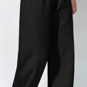 May include: Black wide-leg trousers with an elasticated waistband and side pockets. The trousers are made of a lightweight fabric and have a relaxed fit. A casual style for everyday wear.