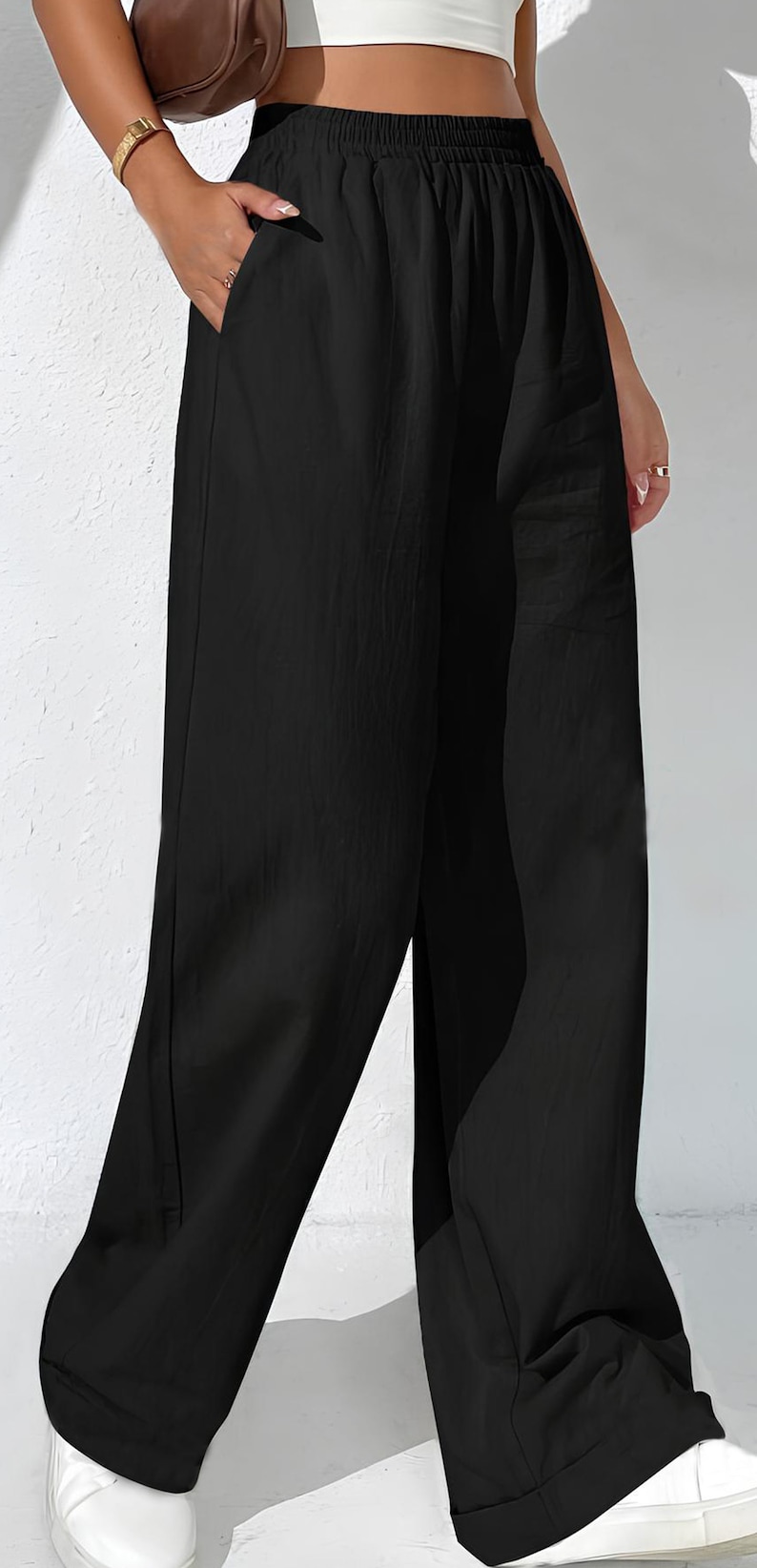 May include: Black wide-leg trousers with an elasticated waistband and side pockets. The trousers are made of a lightweight fabric and have a relaxed fit. A casual style for everyday wear.