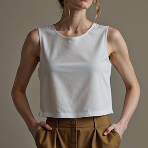 May include: A white sleeveless cropped top with a round neckline. The top is made of a soft, comfortable fabric and has a relaxed fit.