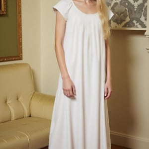 May include: A white cotton nightgown with a scoop neck and short sleeves. The gown has a ruffled hem and is floor-length.
