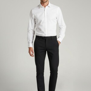 May include: A person wearing a white long-sleeve dress shirt and black dress pants. The shirt is buttoned up and the pants have a black belt. The person is wearing black dress shoes. The outfit is suitable for formal occasions.