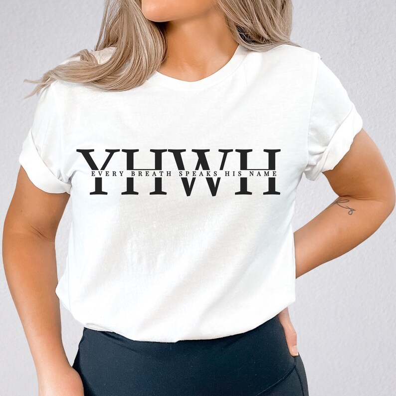 K&ouml;nnte beinhalten: Wei&szlig;es T-Shirt mit dem Wort "YHWH" in gro&szlig;en, fetten, schwarzen Buchstaben &uuml;ber dem Satz "EVERY BREATH SPEAKS HIS NAME". Das T-Shirt hat kurze &Auml;rmel und einen Rundhalsausschnitt.
