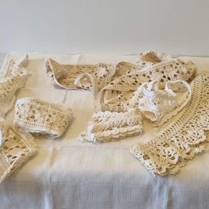 Może przedstawiać: Zestaw białych koronowych lamówek wykonanych na szydełku, z różnymi wzorami i fakturami. Lamówki koronowe są ułożone na białym tle z tkaniny.