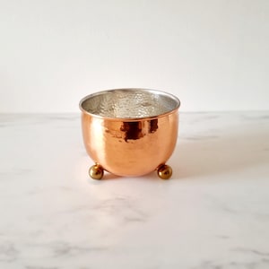 May include: A hammered copper planter with a silver interior and three gold feet.