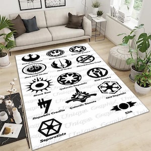 May include: White rectangular area rug featuring various black logos and text from a science fiction franchise. Logos include Rebel Alliance, Jedi Order, and Galactic Republic. The rug is placed in a living room setting.