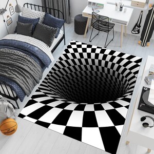 May include: Black and white checkered rug with a 3D optical illusion of a hole in the center. The rug is on a white floor with a bed and a chair in the background.