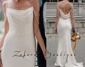 Robe de mariée sirène chic en satin sans bretelles, sans manches, ornée de perles avec de fines bretelles, de pompons et d'une longue traîne élégante