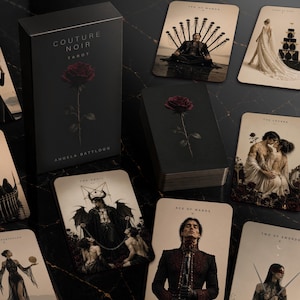 Könnte beinhalten: Ein Couture Noir Tarot-Deck von Angela Battlogg mit einer schwarzen Schachtel und einer roten Rosenillustration. Das Set enthält Karten mit cremefarbenen Hintergründen und dunklen, detaillierten künstlerischen Darstellungen von Figuren.