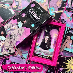 Op de afbeelding: Een set The Cosmic Tarot kaarten met een zwarte doos voorzien van ruimte-illustraties en een roze omlijste tray. De kaarten tonen kleurrijke, gestileerde kunstwerken van figuren, eenhoorns en hemellichamen met bijbehorende tekstlabels.