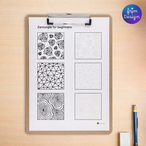 A clipboard holds a Zentangle for beginners worksheet. The worksheet features six square patterns, three on the left in black and white, and three in light gray for tracing on the right side. A blue pen and white eraser are on the wooden surface.