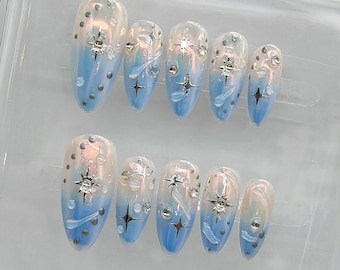 May include: Set of ten blue and white ombre press-on nails with silver glitter and star accents.
