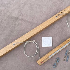 May include: Wooden curtain rod components, including a long rod with cutouts, a smaller rod, a remote control, and mounting hardware. The rods are light brown, and the hardware is silver and blue.