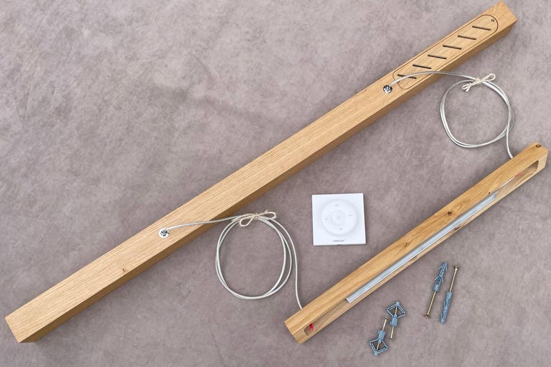 May include: Wooden curtain rod components, including a long rod with cutouts, a smaller rod, a remote control, and mounting hardware. The rods are light brown, and the hardware is silver and blue.