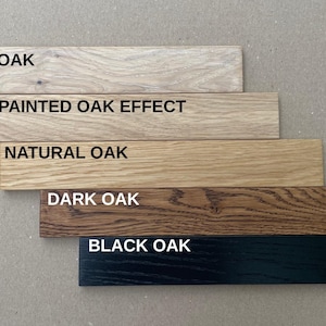 May include: Five wooden planks showcasing different oak finishes: White Oak, Unpainted Oak Effect, Natural Oak, Dark Oak, and Black Oak. Each plank has the finish name printed in white.