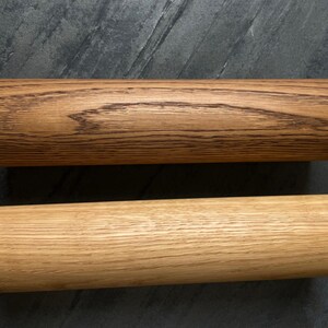 May include: Two cylindrical wooden objects with black cords attached. One is a light brown color, and the other is a darker brown with visible wood grain. The objects are likely handles or decorative elements.