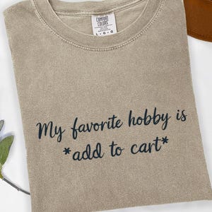 Moje ulubione hobby to koszulka „Dodaj do koszyka”, prezent dla miłośnika zakupów, zabawny cytat o zakupach, humor związany z terapią detaliczną, sarkastyczny żart o zakupach online
