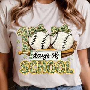 Pode incluir: Camiseta bege com um design para os "100 dias de escola". O design inclui duas bolas de beisebol com laços de camuflagem, um bastão de beisebol e o texto "dias de escola" e "100" em um padrão de camuflagem. Estrelas verdes também estão incluídas.