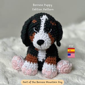 Puede incluir: Un cachorro de perro de montaña bernés tejido a ganchillo, con detalles en negro, blanco y marrón. El cachorro tiene patas rosas y blancas y forma parte de la colección Bernese Mountain Dog Universe. Incluye el texto "Bernese Puppy Edition Pattern".