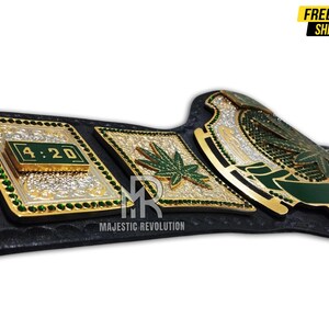Pode incluir: Um cintur&atilde;o de campeonato dourado e verde com um design de folha de maconha. O cinto tem uma al&ccedil;a preta e uma placa central grande com as palavras "Stoned" e "4:20" nela.