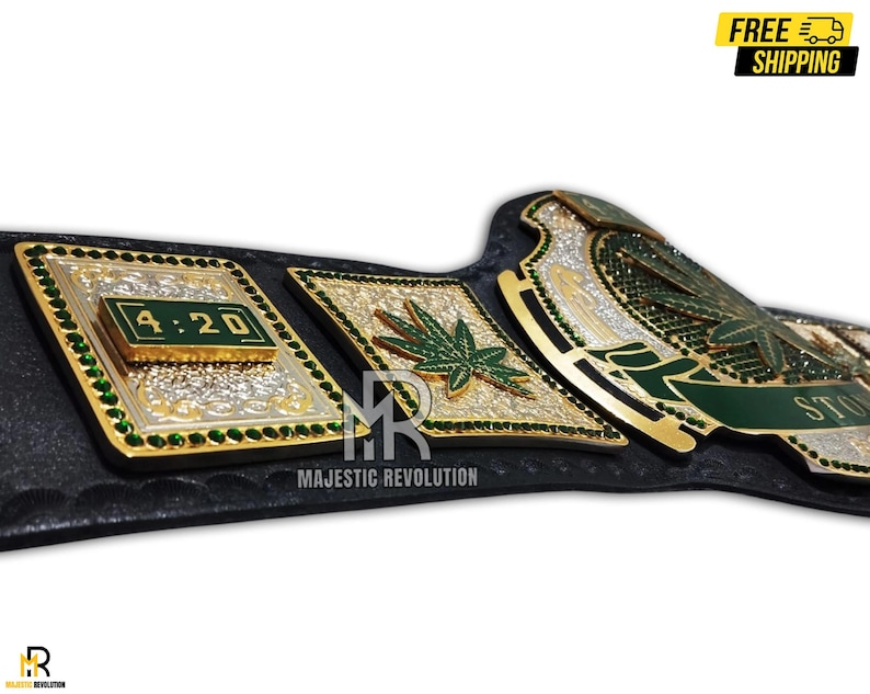 Pode incluir: Um cintur&atilde;o de campeonato dourado e verde com um design de folha de maconha. O cinto tem uma al&ccedil;a preta e uma placa central grande com as palavras "Stoned" e "4:20" nela.