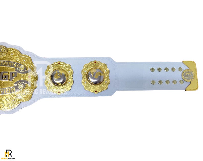 May include: A white and gold championship belt with intricate detailing. The belt features gold medallions and accents, with the words "CONTINENTAL GP CHAMPION" visible. The design includes a white strap with gold edges and rivets.