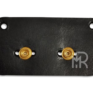 May include: Black leather patch with two gold-colored metal snaps.