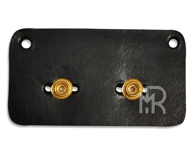 May include: Black leather patch with two gold-colored metal snaps.