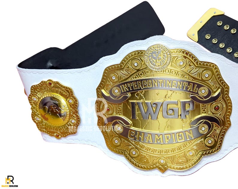 May include: A gold and silver Intercontinental I.W.G.P. Champion wrestling belt with a white strap. The belt features intricate detailing, including the words "Intercontinental I.W.G.P. Champion". The belt has a black backing and a gold buckle.