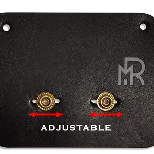 May include: Black leather strap with two adjustable brass buckles. The strap has the letters "MR" embossed in the center.