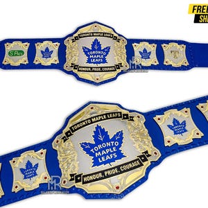 May include: A blue and gold championship belt featuring the Toronto Maple Leafs logo. The belt has a large central plate with the team name and a maple leaf, and smaller plates with the team logo and the text "Honour, Pride, Courage."