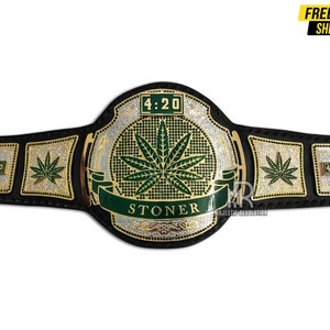 Pode incluir: Um cintur&atilde;o de campeonato preto e dourado com um design de folha de maconha verde. O cinto apresenta as palavras "Stoner" e "4:20" na frente.