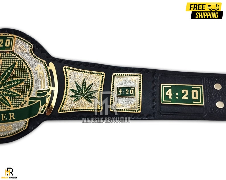 Pode incluir: Um cintur&atilde;o de campeonato de luta livre de couro preto com detalhes dourados e prateados. O cintur&atilde;o apresenta um design de folha de maconha verde, as palavras "4:20" e o texto "Majestic Revolution".