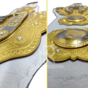 May include: Close-up of a gold and silver championship belt with intricate detailing. The belt features the word "CHAMP" and a globe design, with clear gemstones. The design is set against a white background.