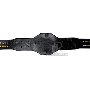 May include: Black leather wrestling championship belt with gold metal accents and rivets. The belt has two rows of gold rivets on each side.