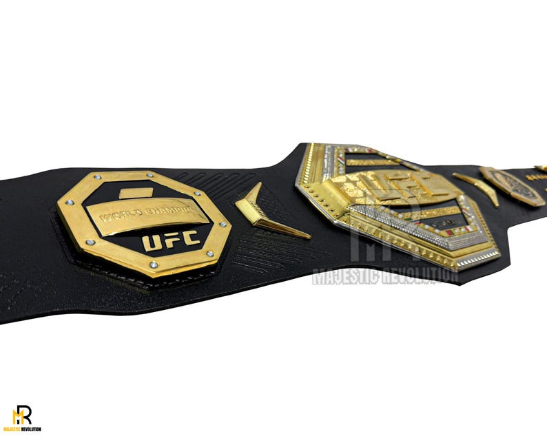 May include: A black leather UFC championship belt with gold and silver accents. The belt features a large octagon-shaped plate with the words "World Champion" and "UFC" in gold lettering.
