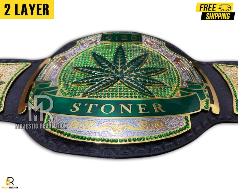 Pode incluir: Um cintur&atilde;o de campeonato verde e dourado com um design de folha de maconha e a palavra "STONER" em uma faixa verde. O cinto &eacute; feito de couro e tem uma fivela dourada.