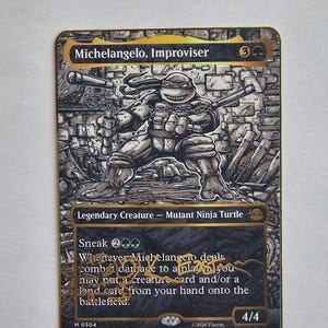 May include: A collectible trading card featuring Michelangelo, Improviser, a legendary creature mutant ninja turtle. The card has a black and gold border, a detailed black and white illustration of the character, and gold ink text signature.