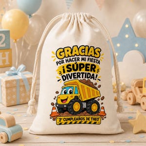 May include: A cream-colored fabric drawstring bag featuring a graphic of a yellow dump truck, orange traffic cones, and the text "GRACIAS POR HACER MI FIESTA ¡SÚPER DIVERTIDA! 2º CUMPLEAÑOS DE THEO" printed in black, yellow, and orange ink.