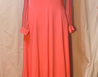 May include: A long, pink dress with sheer sleeves and a V-neckline. The dress is made of a smooth, flowing fabric and has a simple, elegant design.