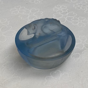 Può includere: Una ciotola di vetro blu chiaro con una finitura opaca e un design di pesce scolpito sul bordo.