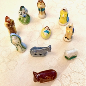 Può includere: Una collezione di piccole statuine in ceramica dipinte a mano raffiguranti un presepe. Le figure includono Maria, Giuseppe, Gesù bambino e i tre re magi. Le statuine sono in vari colori, tra cui blu, giallo, marrone e verde.
