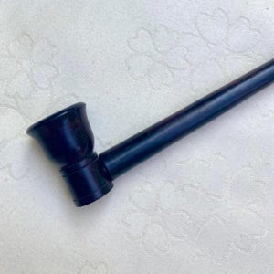 Op de afbeelding: Een donkerbruine houten pijp met een gebogen ketel en een lange, rechte steel. De pijp is gemaakt van donker hout en heeft een gladde, gepolijste afwerking. De ketel is licht uitlopend en de steel is cilindrisch.