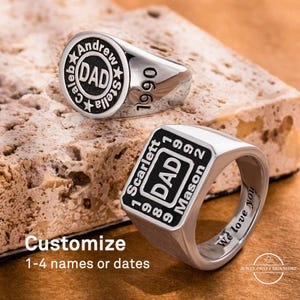 May include: Two silver rings with black lettering. One ring has "DAD" in the center, surrounded by names and the year "1990". The other ring has "DAD" in the center, with names and years around it. The text "Customize 1-4 names or dates" is also visible.