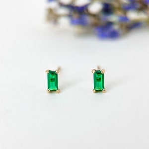 May include: A pair of gold earrings with emerald green rectangular gemstones.