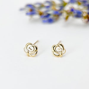May include: A pair of gold rose-shaped stud earrings. The earrings are delicate and have a simple design.